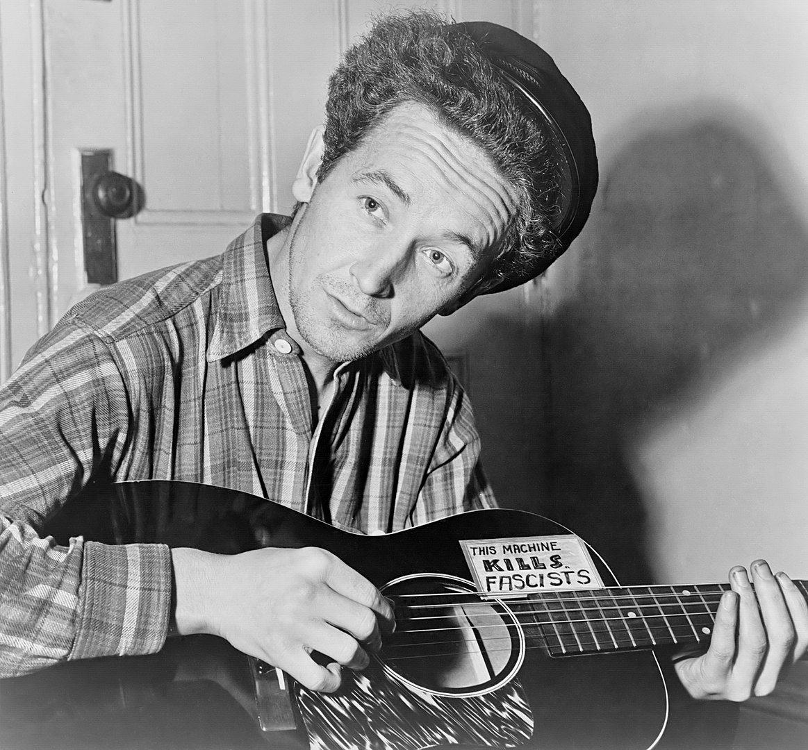 Woody Guthrie amb la seva guitarra, on hi havia enganxat un adhesiu que clamava 