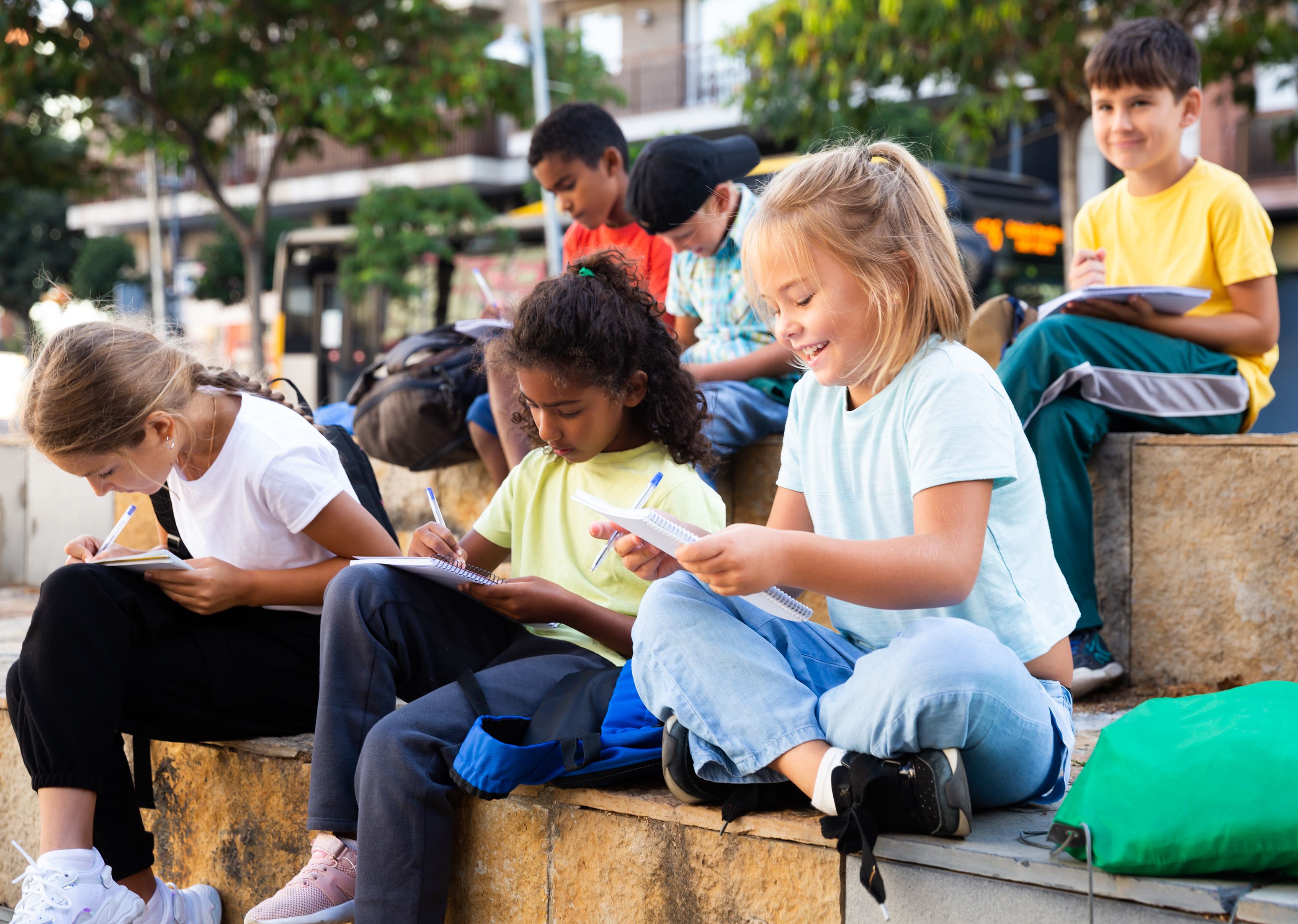 Portrait,Of,Multinational,Group,Of,Kids,Writing,In,Notepads,During
